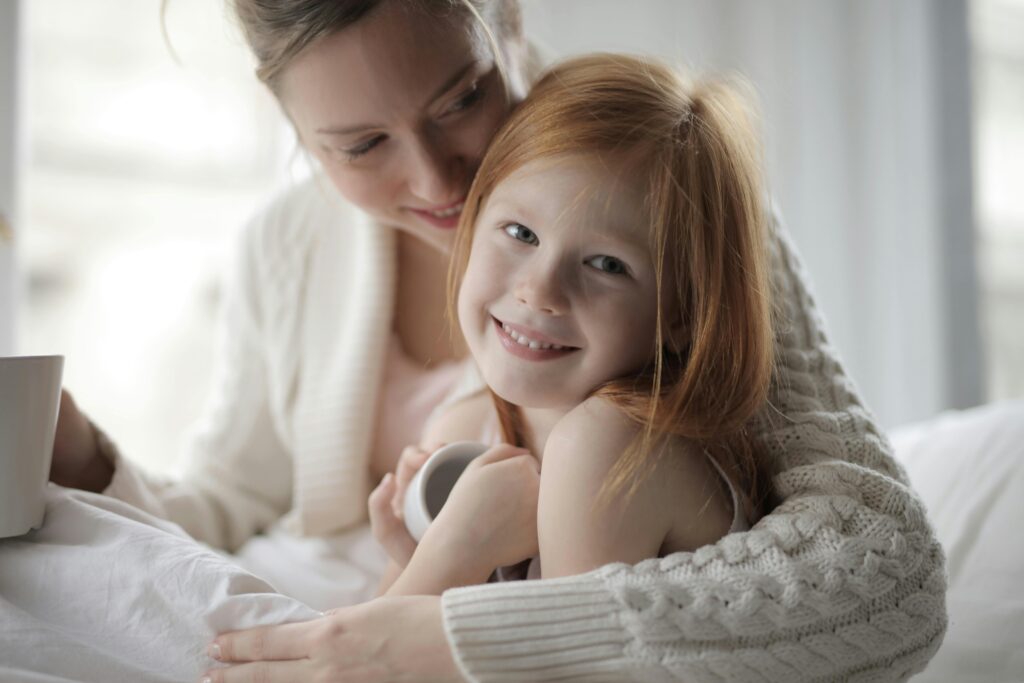 Warm indoor portrait of a mother embracing her young daughter, sharing a cozy moment.